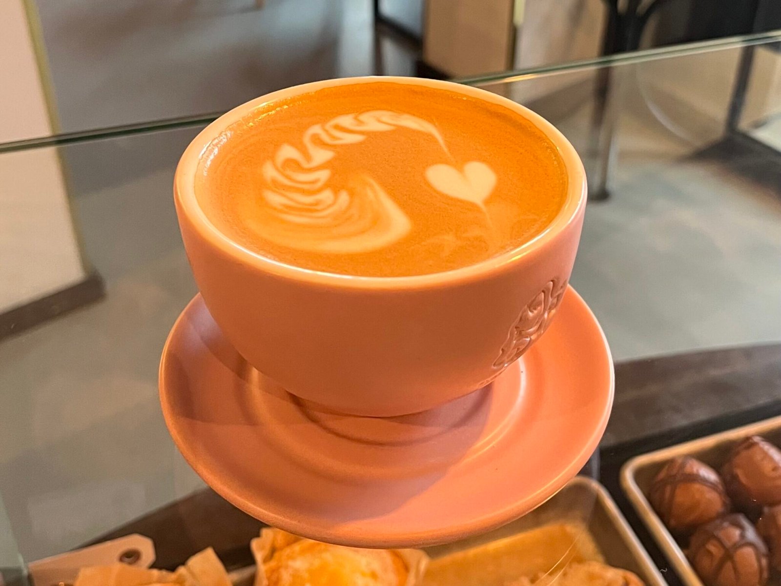 Nærbillede af latte art med hjertemotiv i en rosa kop på Stillestund Kaffebar