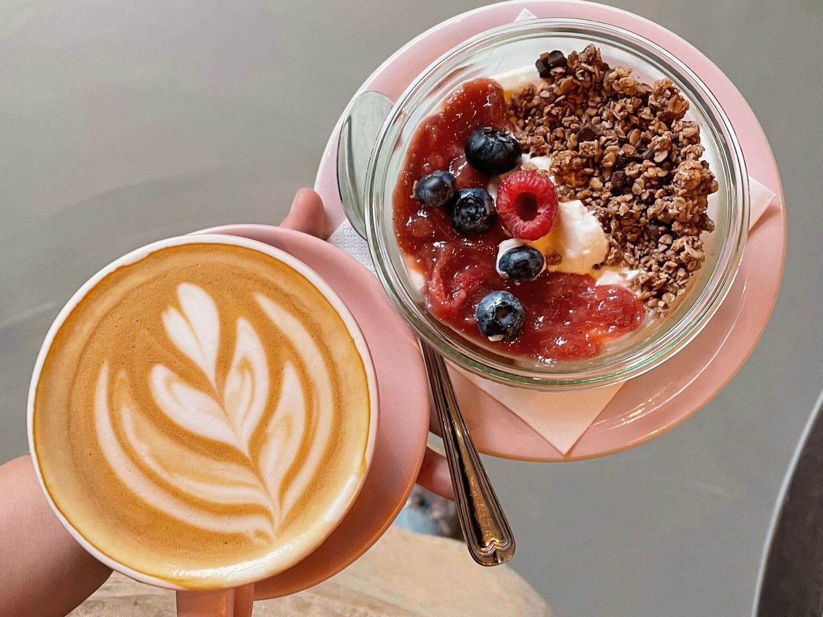 Morgenmadsskål med granola, bær og yoghurt ved siden af en flat white på Stillestund